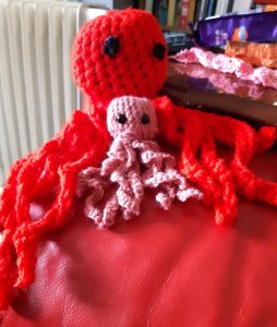 A large red crocheted octopus and a smaller pink one